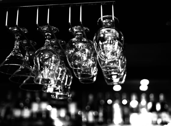 A row of empty cocktail glasses hanging from a bar ceiling