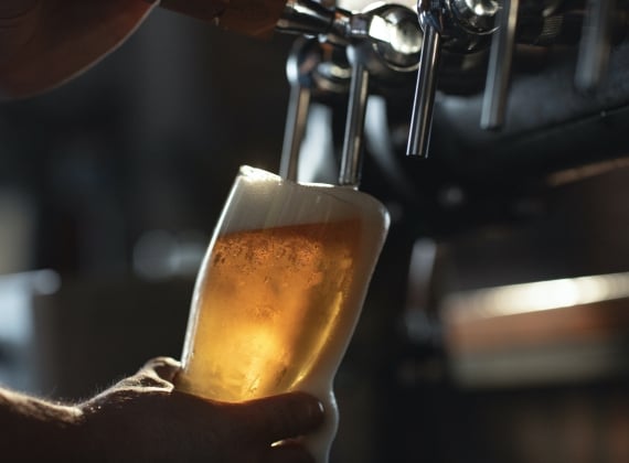 A slightly overflowing draught beer being poured.