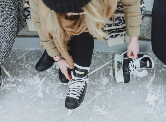 An overhead view of a woman lacing up her ice skates.