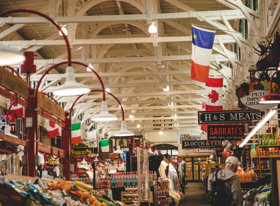 Inside of an indoor market with various stalls and some shoppers.