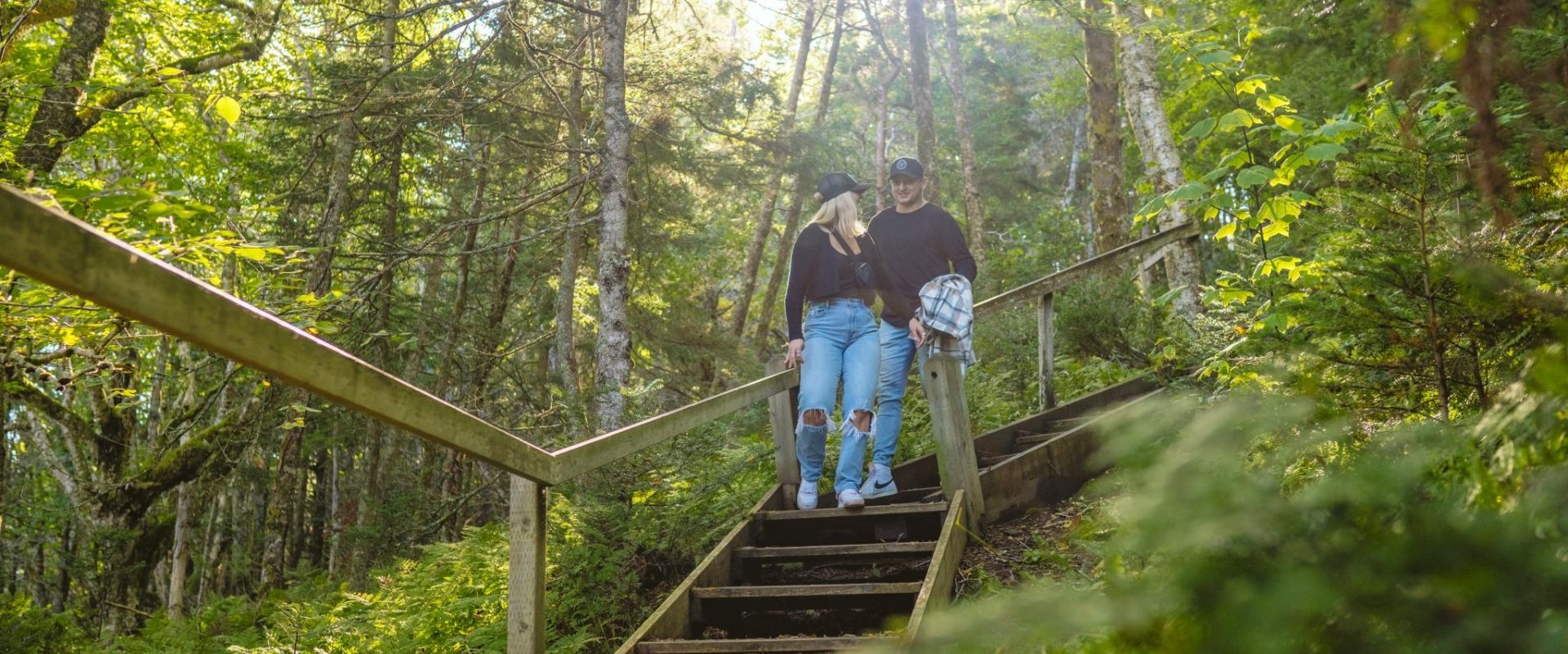 A couple on a park hike descends a wooded stairwell