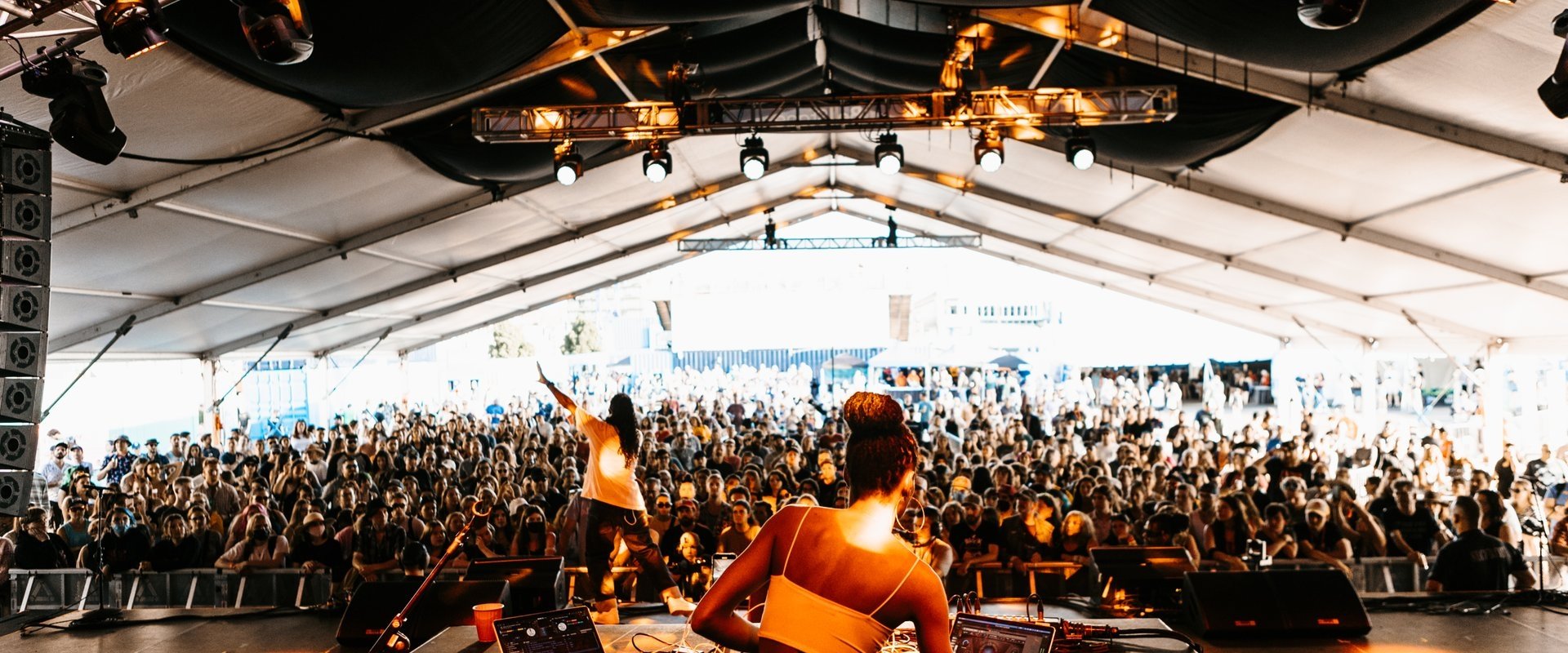 A woman DJs to a large, excited crowd.