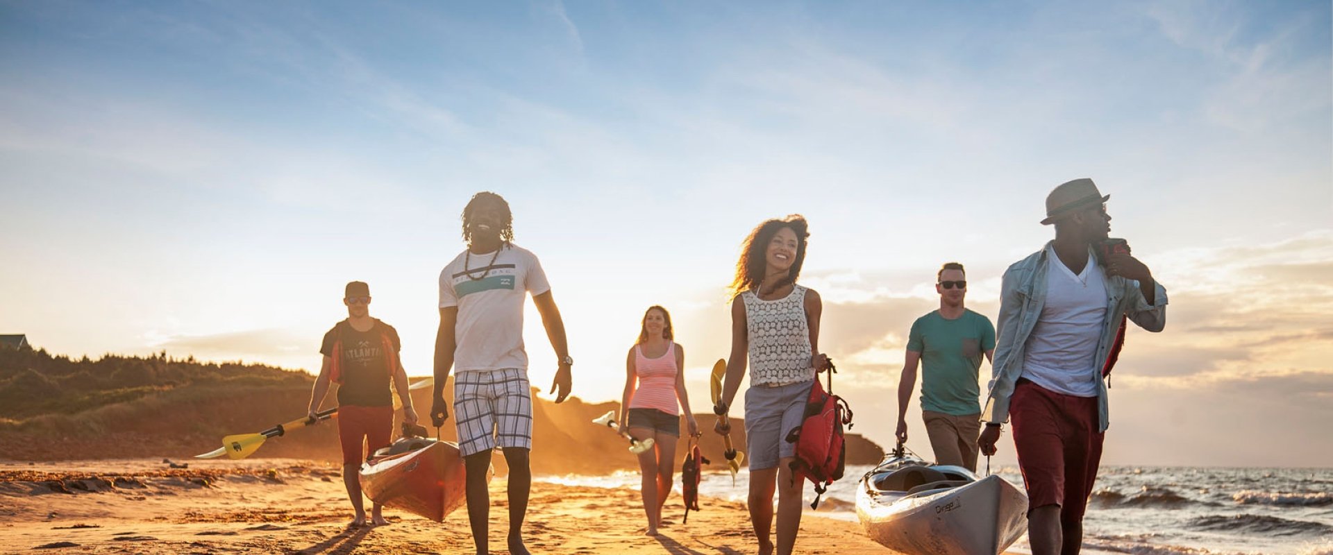 Surfers carry kayaks across the beach