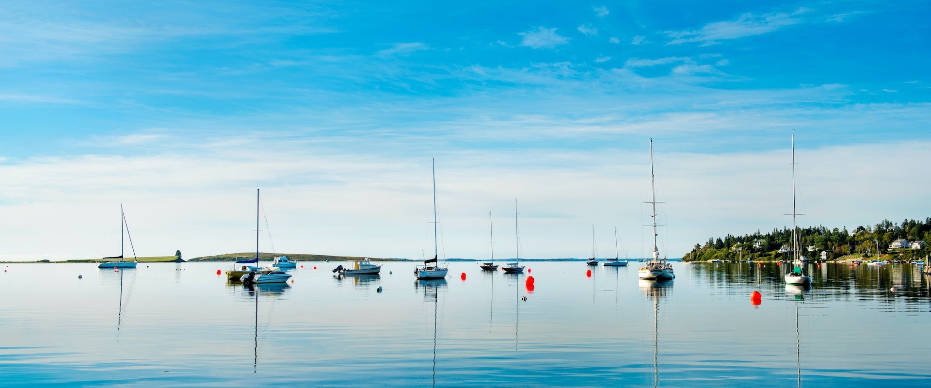 Sailboats with their sails down on still water in the sun.